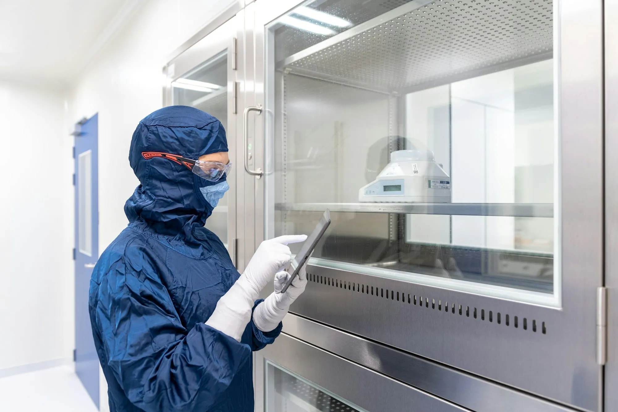 Pracownik w stroju ochronnym z tabletem w laboratorium